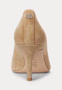 Beige semišová lodička na vysokém podpatku s špičatou špičkou, štíhlým podpatkem a stříbrným logem RL na zadní straně. Hladký povrch.
