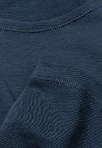 Dunkelblaues T-Shirt aus einem glatten Stoff mit Rundhalsausschnitt und kurzen Ärmeln. Sichtbare Nähte entlang der Kanten.