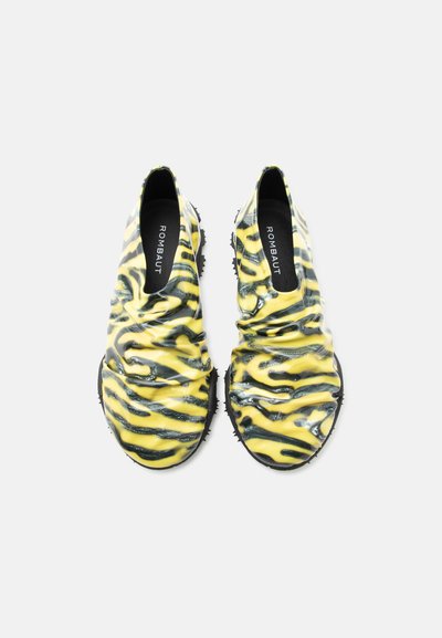 Ζευγάρι κίτρινων και μαύρων μοκασίνια με ρίγες τίγρης, με ρυτιδωμένη υφή και μαύρες σόλες, με την επιγραφή "ROMBAUT" στο εσωτερικό.