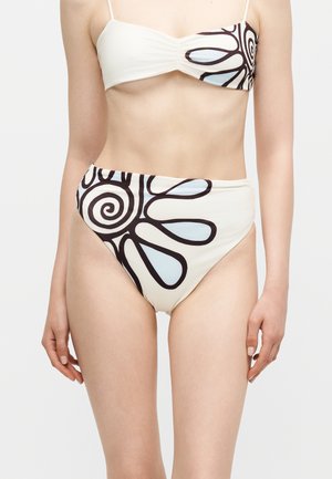Kobieta w dwuczęściowym bikini z czarno-jasnoniebieskim abstrakcyjnym wzorem spirali na białej tkaninie, pokazana od szyi do górnej części ud.