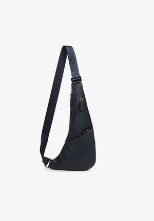 Sling bag in dark navy leather, featuring a sleek, asymmetrical shape, two zippered pockets, and an adjustable strap with logo detailing.