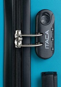 Maleta rígida con una superficie texturizada de color azul brillante, que presenta un cierre negro con combinación, herrajes plateados y un sistema de cierre seguro.