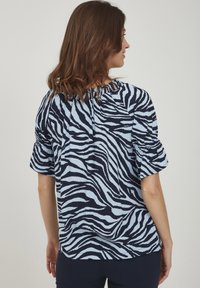 Blå och svart zebra-mönstrad blus med korta puffärmar, samlad halsringning och en avslappnad passform, tillverkad av lättviktigt tyg.