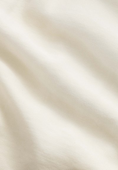 Cream-colored fabric with visible fine weave and soft, flowing folds creating gentle shadows and texture.