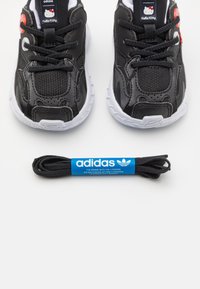 Svarta Adidas-sneakers med ovandel i mesh och syntetiska detaljer, vita sulor och en Hello Kitty-logotyp. Inkluderar ett svart skosnöre.