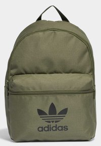 Zeleni platneni ruksak s zaobljenim vrhom, prednjim džepom na zatvarač i crnim Adidas trefoil logotipom. Ima gornju dršku i podešive naramenice. Glatka tekstura.