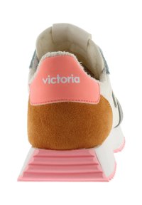 Färgglad sneaker med en mjuk mocka häl i orange, vit ovandel med blå detaljer, rosa sula och en logga på baksidan.