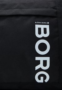 Svart stoffpose med stor hvit tekst "BORG" på den ene siden og "BJÖRN BORG" over. Holdbart materiale med en teksturert overflate.