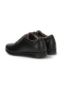 Zapatos de cuero negro con punta redonda, textura suave, diseño minimalista y cuello acolchado. Suela de goma con patrón de relieve circular.