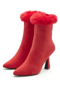 Red suede ankle boots with a pointed toe and a fluffy red faux fur trim at the top. Stiletto heel, smooth texture, sleek design.