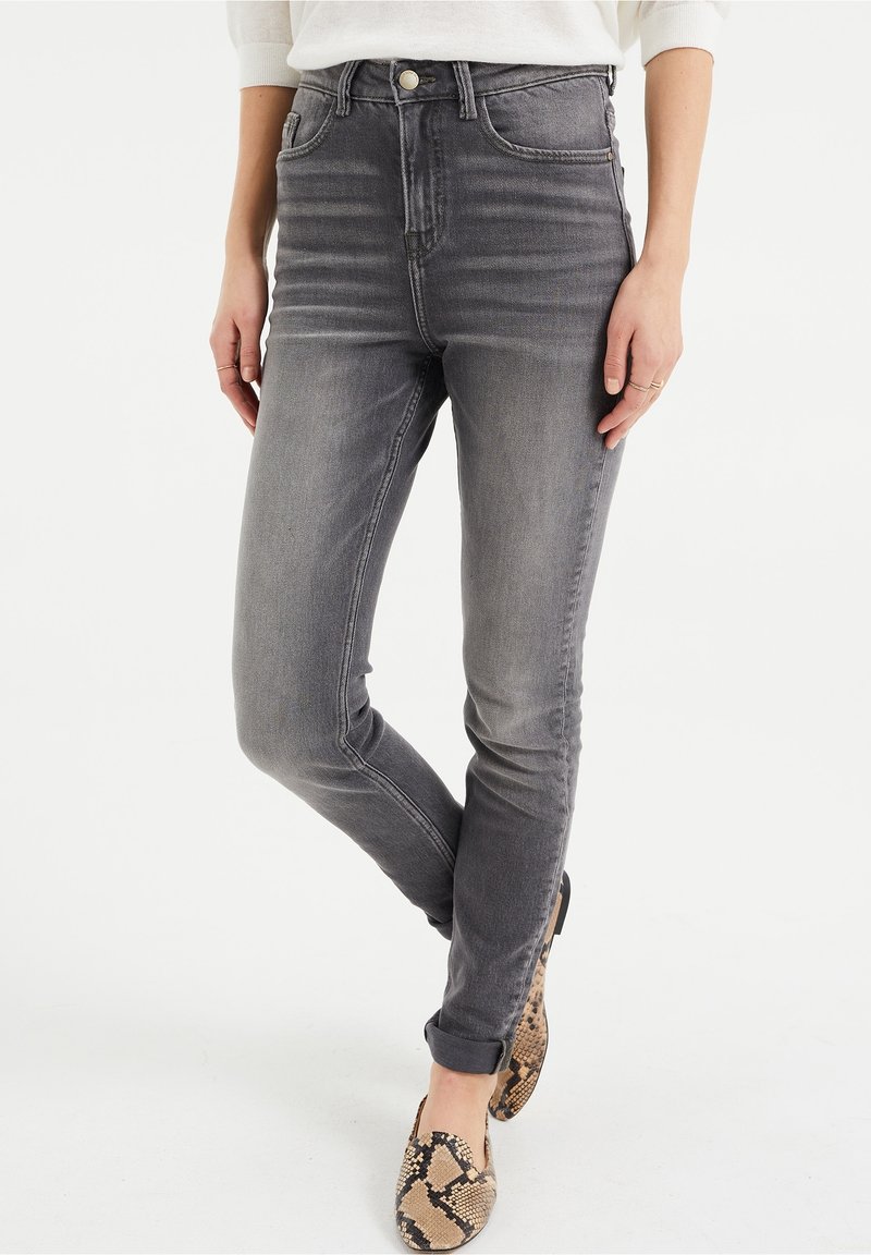 High-waisted gray denim jeans with a slim fit, featuring a subtly faded wash and side seam detailing, paired with animal-print slip-ons.