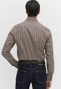 Tjekket skjorte i brun, navy og creme polyesterblanding. Har lange ærmer og almindelig krave, parret med mørke denimbukser.