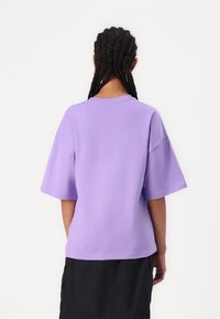 Tricou cu mânecă scurtă, violet, din bumbac moale. Croială relaxată, cu guler rotund și umeri căzuți, are o textură fină.
