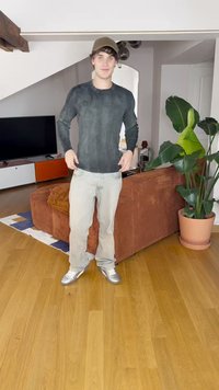 Μακρυμάνικο, σκούρο γκρι ριγωτό πουκάμισο συνδυασμένο με ανοιχτόχρωμα τζιν και γυαλιστερά ασημένια sneakers. Εσωτερικός χώρος με φυτό και καναπέ στο φόντο.