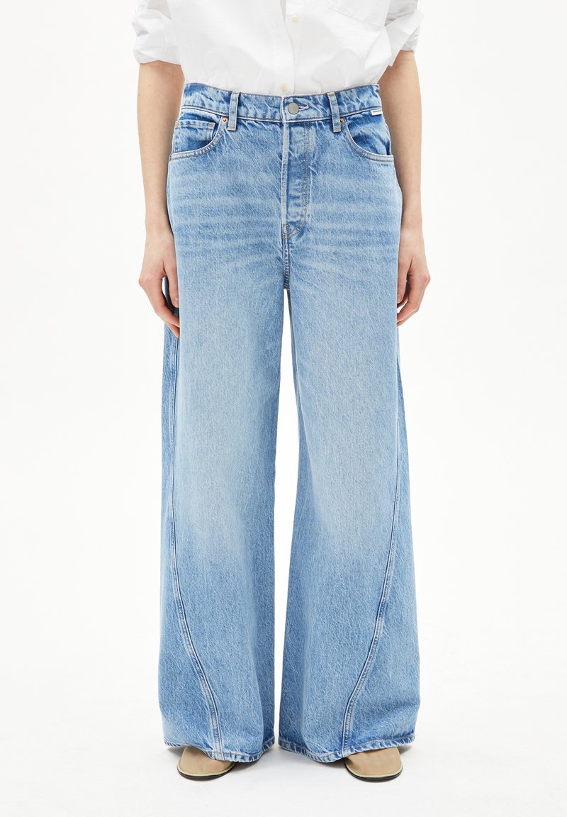 Jean large en denim bleu clair avec taille haute, comportant cinq poches, une fermeture à bouton et un léger délavage sur le tissu.