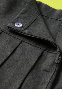 Col de chemise en tissu noir avec un bouton bleu et une ouverture zippée. Présente une surface texturée avec des plis subtils.