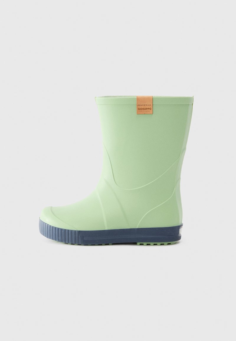 Bota de lluvia de goma verde con un acabado suave, que presenta una suela texturizada en color marino y una etiqueta de cuero color marrón en la parte trasera.