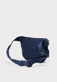 Τσαντάκι χιαστί από νάιλον σε ναυτικό μπλε, με κύριο διαμέρισμα με φερμουάρ, ρυθμιζόμενο λουρί και κλείσιμο με αγκράφα. Λεπτή υφή με μίνιμαλ σχεδιασμό.
