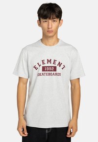 Šedé tričko s krátkým rukávem a kulatým výstřihem. Obsahuje vínový potisk "ELEMENT 1992 SKATEBOARDS" přes hrudník. Klasický střih, bavlněný materiál.