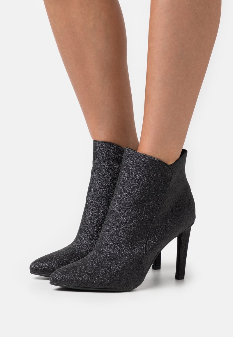 Schwarze Glitzer-Ankle-Boots mit spitzer Zehe und schmalem hohen Absatz. Glatte Textur mit eleganter Form und figurbetontem Schnitt.