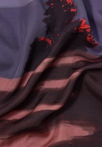 Tekstura tkanine s tekućim uzorcima u tamnim nijansama ljubičaste i smeđe, akcentirana crvenim potezima kista koji prikazuju pejzaž.