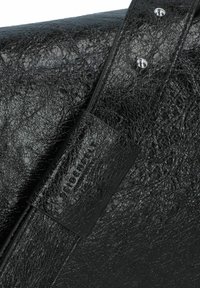 Borsa in pelle nera testurizzata con una finitura liscia, caratterizzata da una forma rettangolare e un sottile etichetta con il marchio, fissata con hardware in metallo.