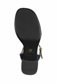 Svart gummisula på en sandal med en texturerad greppmönster. Fotbädden är av marinblå mocka med guldhårdvara för justerbart ankelsnöre.