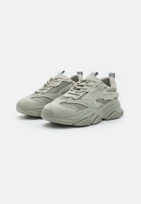 Sneaker verde chiaro con texture, pannelli in rete, suola in gomma spessa e punta rotonda. Presenta chiusura con lacci e linguette in tessuto.