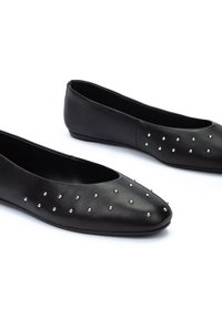 Bailarinas de cuero negro con puntera redondeada, que presentan adornos de tachuelas plateadas en la parte superior y una textura suave. Diseño de perfil bajo.