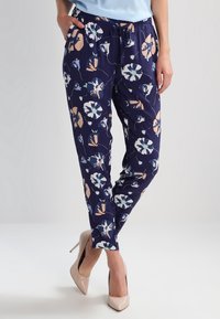 Tmavě modré květinové kalhoty s elastickým pasem a šňůrkou, s bílými, růžovými a modrými akcenty. Hladká textura látky.