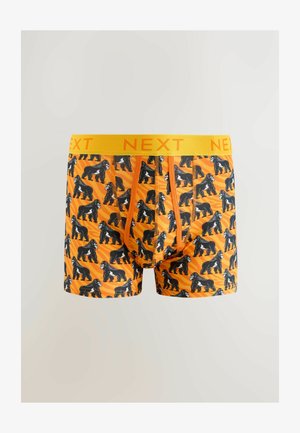 Oranssi puukujousten alushousut, joissa on toistuva musta gorillakuosi, keltainen "NEXT" -vyötärö ja sileä kangas.