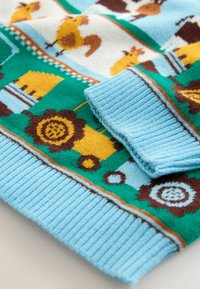 Pulover tricotat cu guler și manșete albastre cu dungi, cu corp verde decorat cu modele de animale de fermă și tractoare galbene.