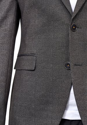 Grau gemusterter Blazer aus strukturiertem Stoff. Verfügt über zwei Knöpfe, eine einzelne Brusttasche und Reverskragen. Weißes Hemd darunter sichtbar.