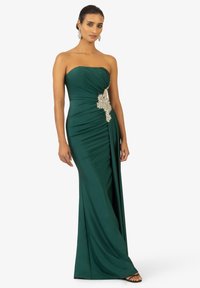 Abito senza spalline verde smeraldo con tessuto arricciato e un'elegante accentuazione floreale in argento in vita. Silhouette liscia ed elegante.