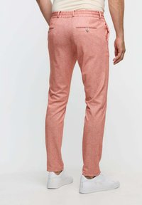 Rosa melerade byxor med elastisk midja, två bakfickor och slim fit, i kombination med vita sneakers.