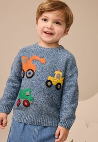 Blauer Strickpullover mit bunten gestickten Designs von Baustellenfahrzeugen: orangefarbener Bagger, gelbes Lastwagen und grüner Lader.