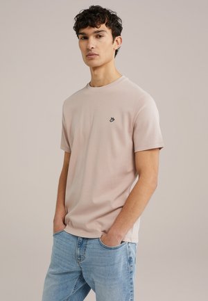 Lichtroze katoenen T-shirt met een ronde hals en korte mouwen, voorzien van een klein zwart logo op de borst. Draag het met lichtblauwe jeans.