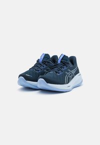Scarpe sportive blu e nere con una tomaia in mesh traspirante, lacci a contrasto e suola imbottita di blu chiaro. Branding evidente sulla linguetta.