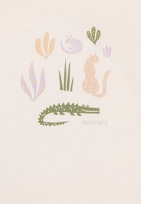 Cremfarbener Stoff mit einem verspielten Design: ein grüner Krokodil, ein geflecktes Tier und verschiedene Pflanzen in Pastellfarben.