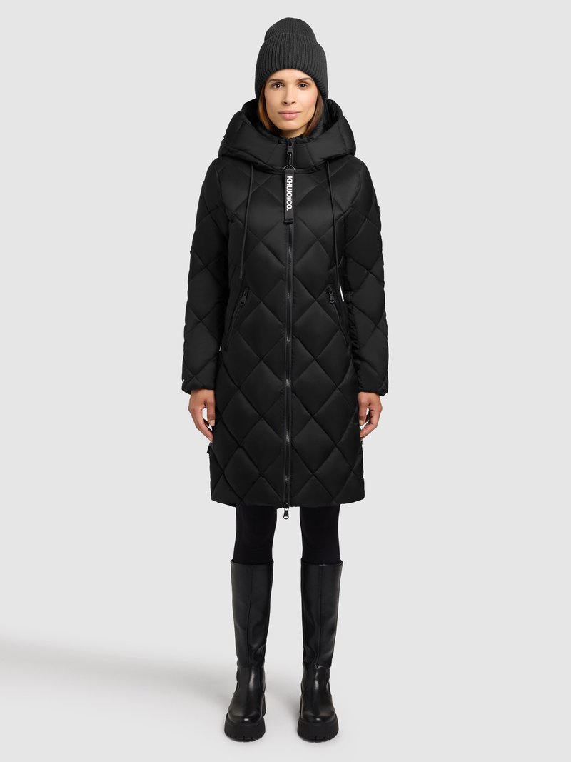 Mustast pehmest tikitud sulejope kapuutsiga, esikinnis tõmblukuga ja kahe küljetaskuga. Sobitatud mustade retuuside ja põlvikutega kõrgete saapadega.