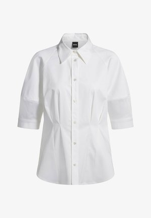 White short-sleeve shirt with a pointed collar, button front, and structured seams. Fabric is smooth with a slight sheen.