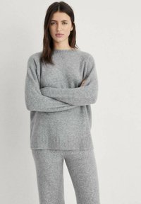 Maglione a maglia grigio chiaro con scollatura rotonda, orlo a costine e vestibilità comoda. Abbinato a pantaloni a maglia grigio chiaro coordinati. Tessuto morbido.