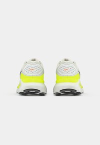 Να παπούτσια τρεξίματος Nike με άσπρο και νεον κίτρινο επάνω μέρος, λεπτομέρειες από δίχτυ και μαύρη καουτσούκ σόλα. Διαθέτει διακριτικό λογότυπο και μαλακή φτέρνα.