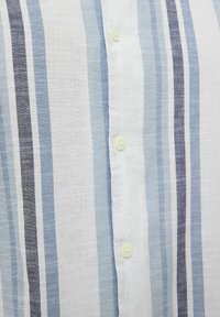 Camisa de botones con rayas verticales en azul claro, azul oscuro y blanco. Fabricada en un tejido texturizado con botones amarillos.