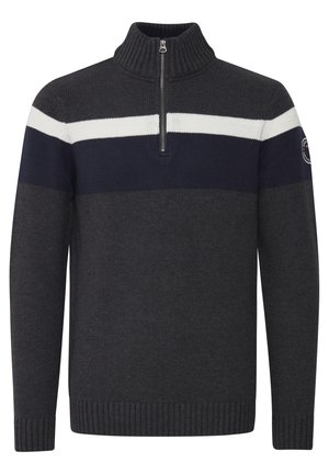 Tamsiai pilkas megztinis su aukštu apykakle, turintis užtrauktuką, su baltomis ir tamsiai mėlynomis horizontaliosiomis juostelėmis per krūtinę. Raukšlėtos rankovių ir apačios kraštai.