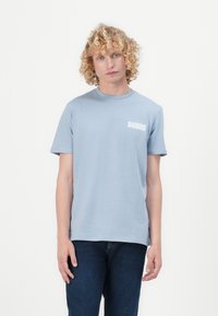 Hellblaues Rundhals-T-Shirt aus Baumwolle, mit kurzen Ärmeln und einem kleinen weißen Logo auf der linken Brustseite.