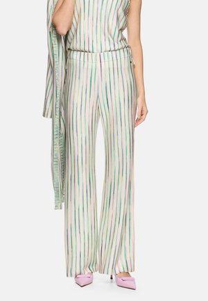 Woman wearing high-waisted, wide-leg pants with vertical green, blue, and beige stripes, paired with light pink pointed shoes.