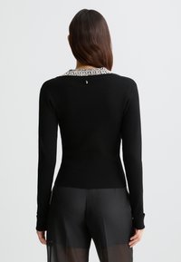 Maglione nero a maniche lunghe con colletto decorativo in perline. La vista posteriore mostra un design aderente e una texture liscia e morbida.