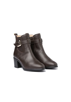 Botines de cuero marrón con puntera redondeada, detalle de hebilla lateral y tacón cuadrado. Textura suave y diseño minimalista.