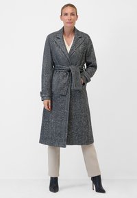 Grå, fläckig yllekappa med notch-krage, knytbälte och långa ärmar, kombinerad med beige byxor och svarta klackstövlar.